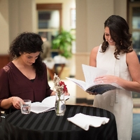 Two people standing at a small table looking through their programs